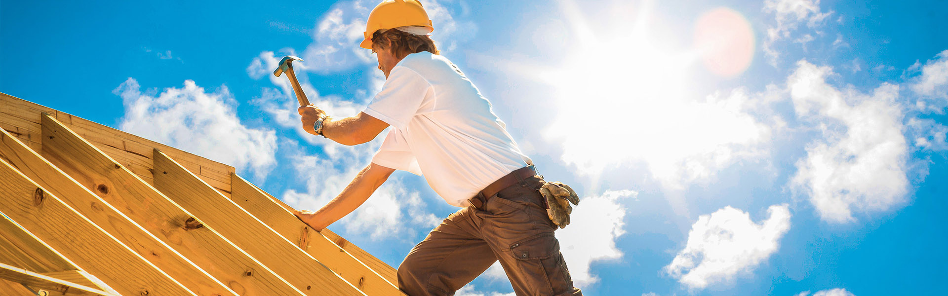 Mann auf dem Dach bei Zimmerarbeiten