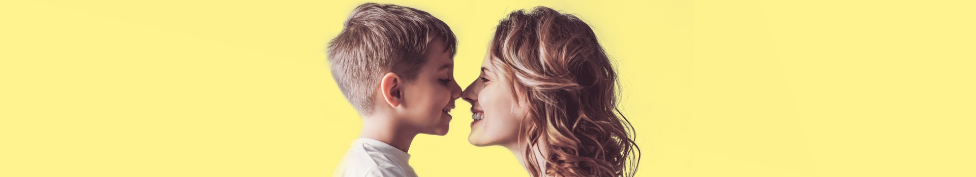 Mutter und Sohn stupsen sich bei der Nase und lachen sich an.