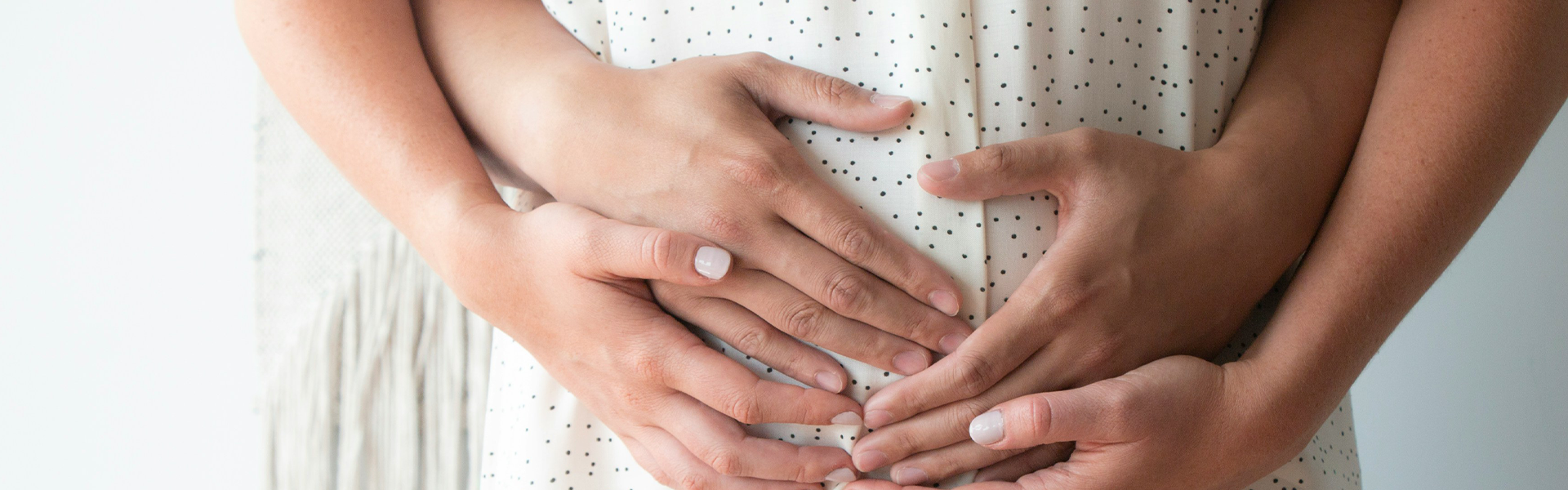 Ein Schwangeres paar hält den Babybauch fest in ihren Händen.