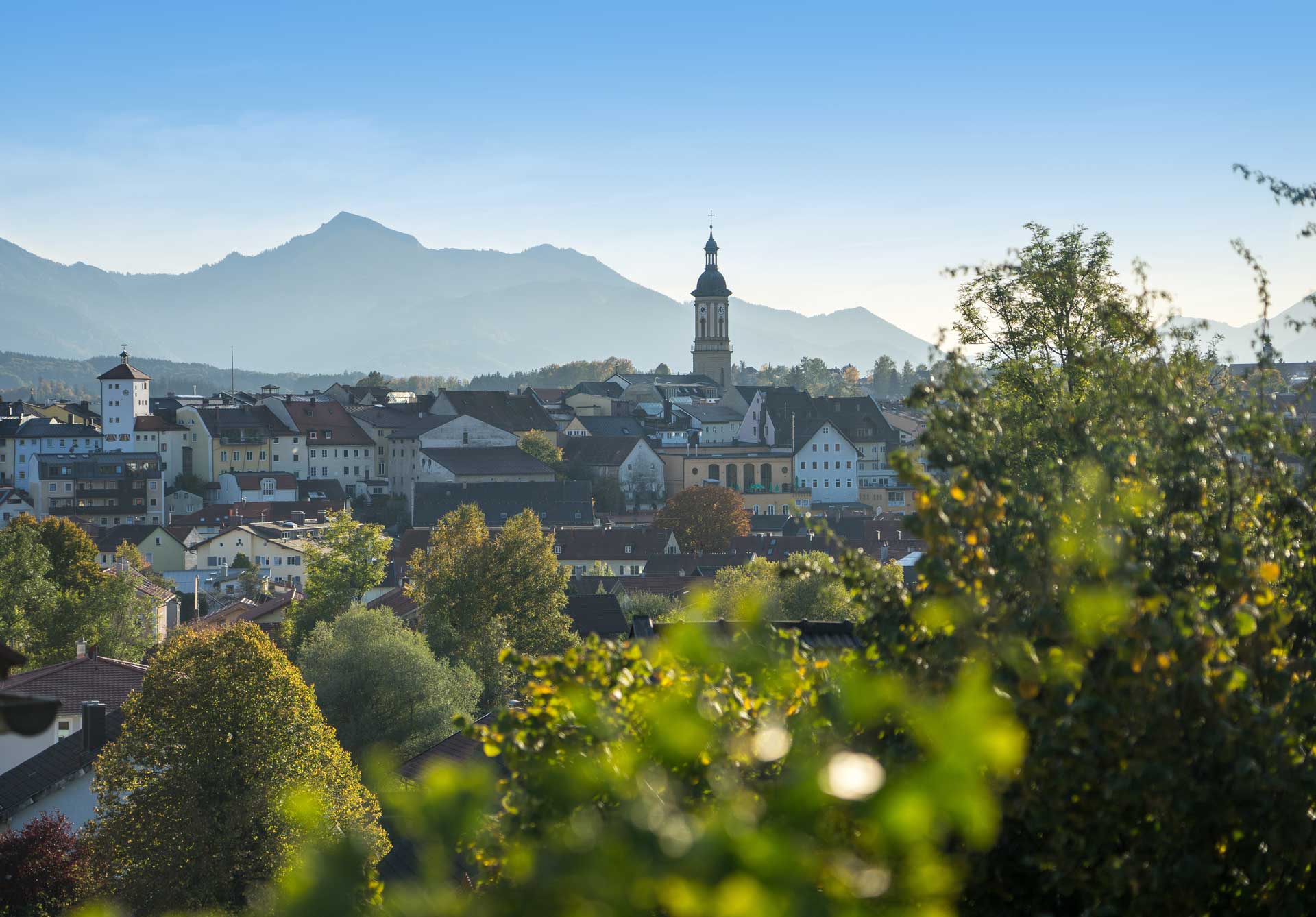 Ein Blick über die Stadt Traunstein mit dem Kirchturm und dem Bergpanorama im Hintergrund.